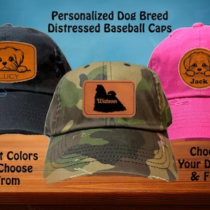 May include: Three distressed baseball caps with personalised dog breed patches. The caps are black, camouflage, and pink. The patches feature a dog's head with the names Lucy, Watson, and Jack.