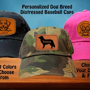 May include: Three distressed baseball caps with personalised dog breed patches. The caps are black, camouflage, and pink. The patches feature a golden retriever, a black labrador, and a golden retriever puppy. The text on the patches reads "Lucy", "Watson", and "Jack".