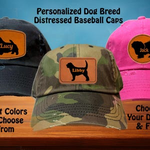 May include: Three distressed baseball caps with personalised dog breed patches. The caps are in black, camouflage, and pink. The patches feature a silhouette of a dog with the name "Lucy", "Libby", and "Jack" on each patch.