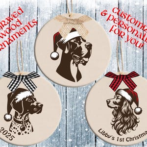 Pode incluir: Três enfeites redondos de madeira gravada, cor creme, com retratos de cães usando gorros de Papai Noel. Cada enfeite tem um design de raça de cão diferente, um laço decorativo e o texto "engraved wood ornaments" e "Customized & personalized for you!"