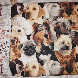 May include: A white fabric pot holder with a pattern of various dog breeds. The pot holder has a red and white border and the words "woof", "mom", "of", "poof", "sniff", and "shift" are printed on the border.