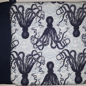 May include: A blue and white fabric pot holder with a pattern of black octopuses. The pot holder has a navy blue backing.
