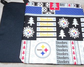 May include: A black and patterned oven mitt featuring the Pittsburgh Steelers logo, snowflakes, and Christmas trees. The mitt has a black loop for hanging and a black interior. The Steelers logo is in yellow, red, and blue.