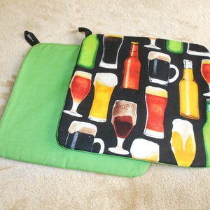 May include: Two green pot holders with a black pot holder with a beer and glass design on top. The design features various beer bottles, glasses, and mugs.