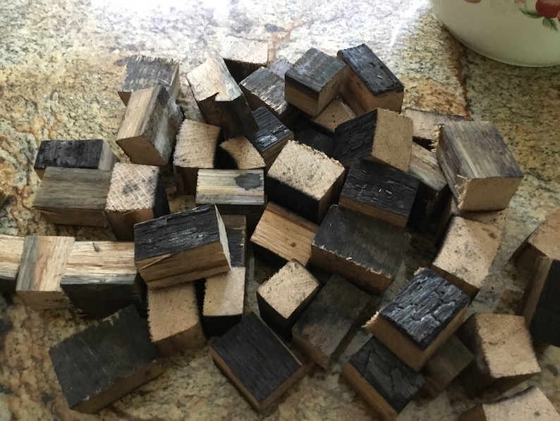 May include: A pile of small, charred wood cubes, some with a natural wood color, others with a dark brown char. The cubes are likely for smoking food.