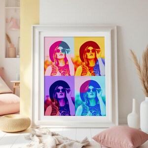 May include: A framed art print featuring a pop art style image of a person wearing sunglasses and a hat. The image is divided into four colorful quadrants: red, yellow, purple, and blue. The print is in a white frame and is displayed in a bright room.