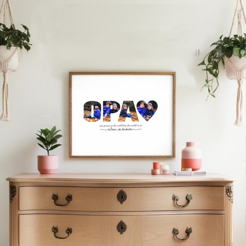 Puede incluir: Un cuadro enmarcado con la palabra "OPA" en negro, con fotos familiares dentro de las letras y una forma de coraz&oacute;n. El texto de abajo dice "one person in the world but the world to us" y una firma.