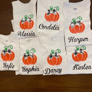 May include: Six white t-shirts with a pumpkin design and a name on each. The names are: Sofie, Sophia, Darcy, Kestlea, Harper, and Cordelia.
