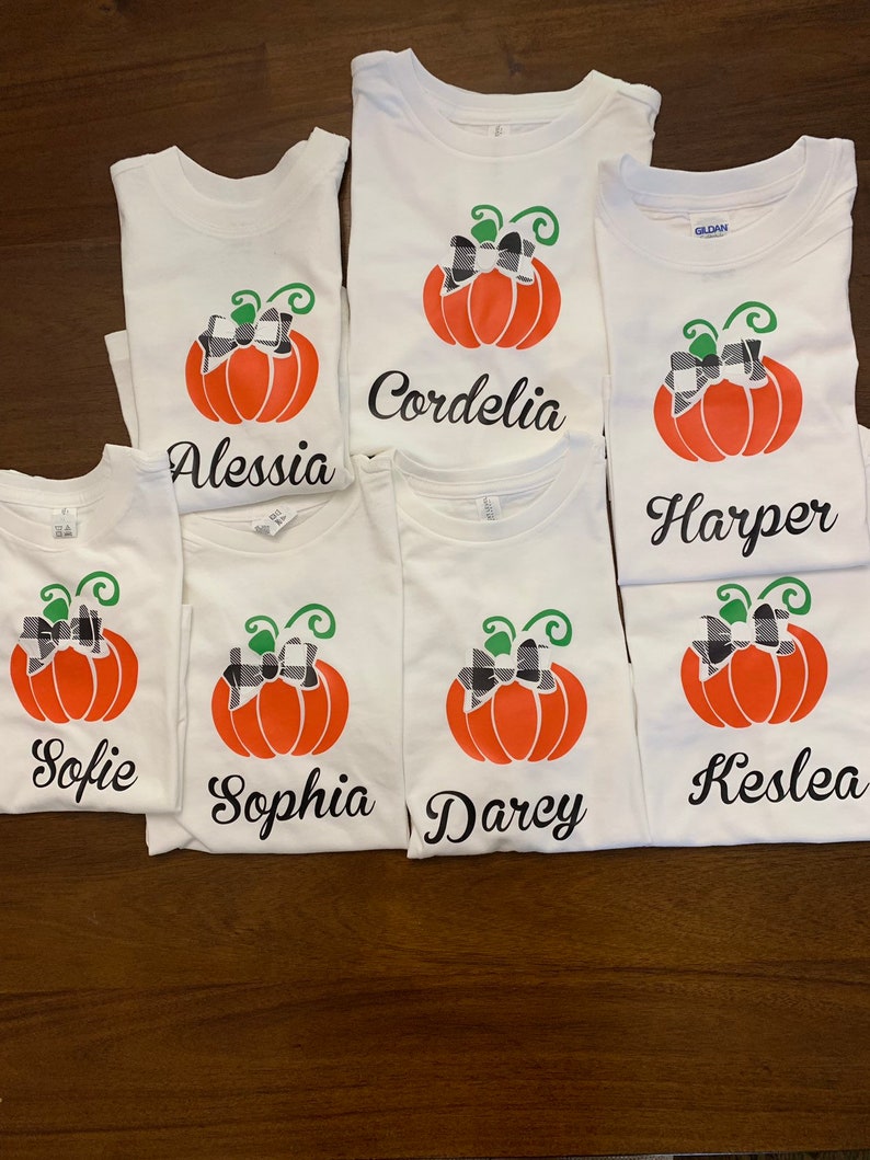 May include: Six white t-shirts with a pumpkin design and a name on each. The names are: Sofie, Sophia, Darcy, Kestlea, Harper, and Cordelia.