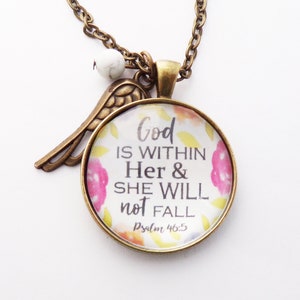 May include: A gold necklace with a round glass pendant featuring a floral design and the text "God is within Her & She Will not Fall Psalm 46:5". The pendant is attached to a small gold angel wing charm.