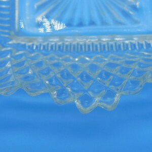Puede incluir: Primer plano del borde inferior de un plato de vidrio transparente con un patr&oacute;n de diamante. El plato tiene un borde festoneado.