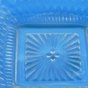 Puede incluir: Un plato de vidrio azul con un patr&oacute;n decorativo en forma de estrella. El plato tiene una forma cuadrada y un borde elevado.
