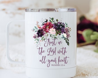 May include: A white stainless steel travel mug with a handle and a clear lid. The front features a floral arrangement in shades of deep purple, burgundy, and pink, with the text Trust in the Lord with all your heart PROVERBS 3:5-6.