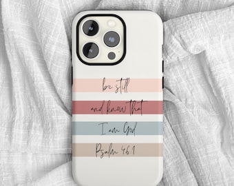 May include: A white smartphone case featuring horizontal stripes in soft shades of pink, dusty rose, slate blue, and beige. The black text printed on the stripes reads, "be still and know that I am God Psalm 46:1" in a cursive and print font combination.