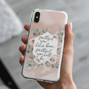 May include: A clear phone case with a pink background and a gold hexagonal frame. The frame contains a floral design and the text "faithful you have been, faithful you will be" with the scripture reference "deut. 7:9".