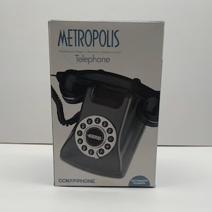 May include: A black "Metropolis" telephone in its original box. The box features the telephone's image, a rotary dial, and the text "Mechanical Ringer, Receiver Volume Control." The brand name "Conairphone" is also visible.