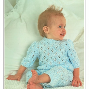 May include: A light blue knitted baby romper with a lacy pattern. The romper is worn by a baby sitting on a white blanket. The text "Peter Pan Mischief Double Knit" and "Wendy" are visible in the image.