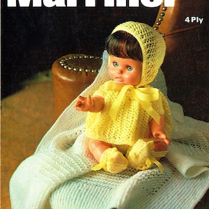 May include: A yellow knitted baby doll outfit with a matching bonnet. The outfit is worn by a doll sitting on a white knitted blanket. The doll has brown hair and blue eyes. The pattern is for 4 ply yarn.