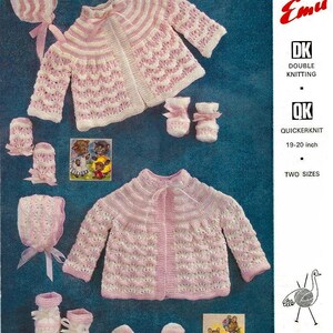 May include: A knitting pattern for a baby set in pink and white. The set includes a cardigan, hat, booties, and mittens. The pattern is for double knitting and quick knit yarn. The pattern is for two sizes. The pattern is from Emu, a brand of knitting patterns.