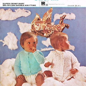 Könnte beinhalten: Zwei Babys tragen gestrickte Strickjacken, eine in Blau und eine in Weiß, und sitzen auf einer wolkenartigen Oberfläche. Das Bild stammt aus einer Strickanleitung für eine "Super Crimp Baby Bri-Nylon Double Knitting" Strickjacke. Die Muster-Nummer ist 8933 und der Preis beträgt 1/- 5p.