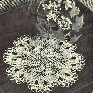 May include: A white crocheted doily with a delicate, intricate design. The doily is circular and has a scalloped edge.
