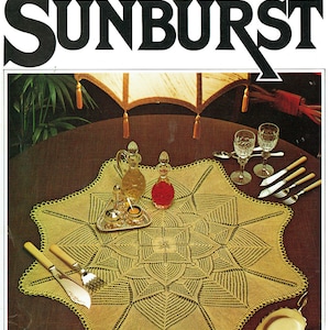 May include: A vintage magazine cover titled "SUNBURST" featuring a detailed, star-shaped, crocheted tablecloth in a light yellow color. The table is set with glassware, silverware, and decorative bottles.