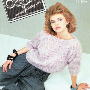 Op de afbeelding: Een roze gebreide trui met een losse pasvorm en 3/4 mouwen. De trui is gemaakt van een geborsteld, dik garen en wordt getoond op een model dat een grijze broek draagt. De tekst "DIANA BRUSHED CHUNKY 76-97 cm 30-38 in" is zichtbaar in de afbeelding.