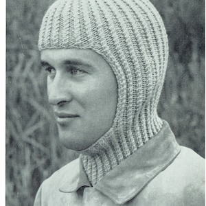 Puede incluir: Primer plano de una persona que lleva una gorra de punto gris con una solapa larga para el cuello. La gorra es de punto de canalé y tiene un diseño sencillo.