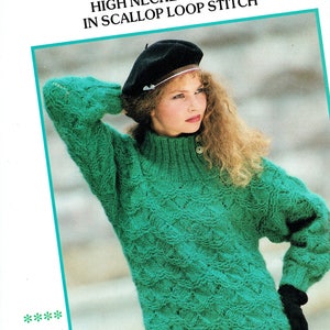 May include: A green high-necked knitted sweater with a scallop stitch pattern. The sweater has decorative buttons on the neck and can be rolled over to create a lower neckline.