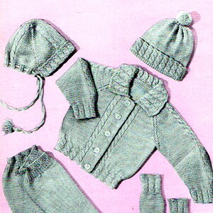 Peut inclure: Un ensemble pour bébé en tricot gris clair, comprenant un cardigan boutonné, un pantalon, deux bonnets et une paire de moufles. L'ensemble présente un motif en tricot torsadé et est présenté sur un fond rose. Le chapeau a un pompon.
