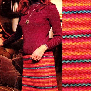 Puede incluir: Una mujer lleva un jersey de cuello alto color granate y una falda larga de crochet a rayas multicolores. La falda tiene rayas de color rojo, naranja, azul verdoso y rosa.