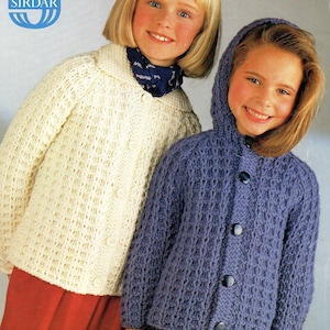 Może przedstawiać: Dwoje dzieci w dzianinowych kardiganach. Dziewczynka po lewej stronie ma na sobie biały kardigan z zapięciem na guziki. Dziewczynka po prawej stronie ma na sobie fioletowy kardigan z kapturem i zapięciem na guziki. Wzór to C4528.