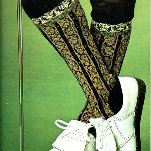 May include: A pair of white leather shoes with black soles and white laces, paired with patterned knee-high socks. The socks feature a black, tan, and green floral design. The background is a solid green.