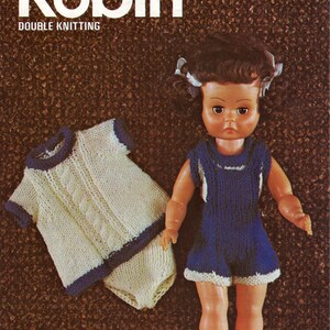 Könnte beinhalten: Ein Strickmuster für ein Puppenoutfit. Das Muster ist für ein weiß-blaues Outfit mit einem Strickoberteil mit Zopfmuster und Shorts. Das Muster ist von Robin Double Knitting und trägt die Nummer 2630.