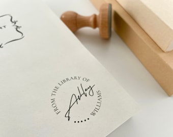 May include: A close-up of a book with a round, black and white stamp that reads "From the Library of Ashley Williams".