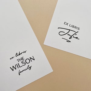 May include: Two white cards with black text. The top card says "Ex Libris" with a handwritten signature below. The bottom card says "ex libris THE WILSON family".