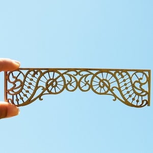 以下が含まれることがあります： 繊細で複雑なデザインの装飾的な木製の切り抜き。切り抜きは渦巻きと円形の繰り返しパターンを特徴とし、視覚的に魅力的で装飾的な境界線を作成しています。