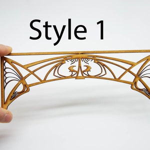 May include: A wooden archway with a decorative Art Nouveau design. The archway is made of laser-cut wood and is unfinished. The archway is labeled "Style 1".