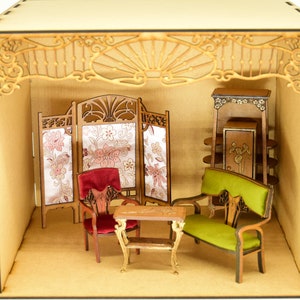 May include: A miniature dollhouse room with a wooden frame and a decorative ceiling. The room is furnished with a green velvet sofa, a red velvet chair, a wooden table, a screen with floral fabric panels, and a wooden cabinet with shelves.