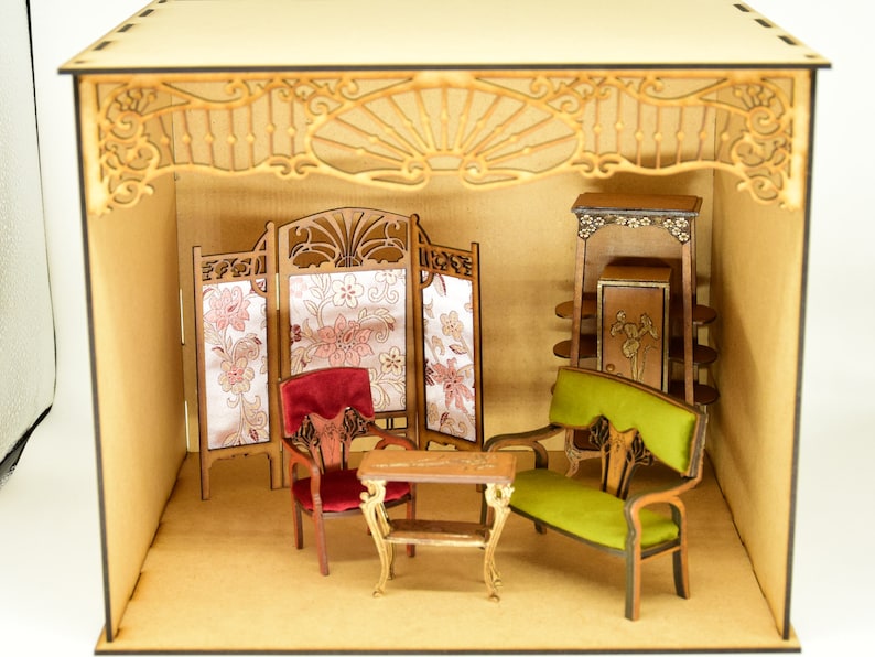 May include: A miniature dollhouse room with a wooden frame and a decorative ceiling. The room is furnished with a green velvet sofa, a red velvet chair, a wooden table, a screen with floral fabric panels, and a wooden cabinet with shelves.