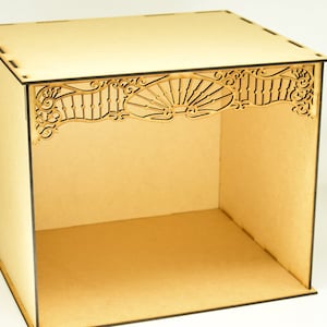 May include: A wooden box with a decorative cutout design on the top. The box is made of light brown wood and has a square shape.