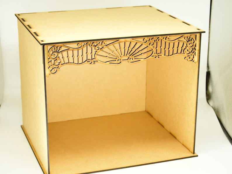May include: A wooden box with a decorative cutout design on the top. The box is made of light brown wood and has a square shape.