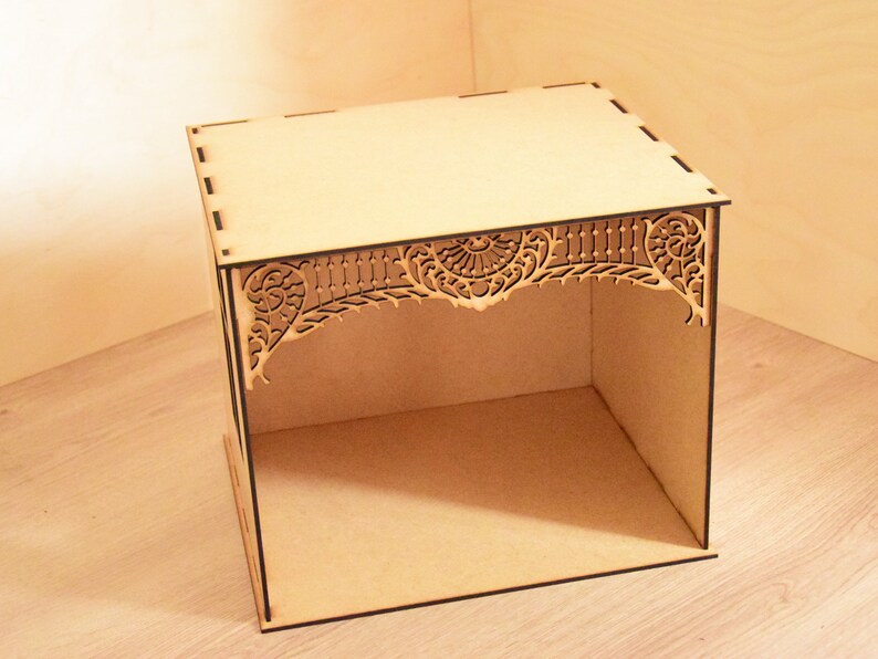 May include: A wooden box with a decorative, laser-cut design on the top. The box is open and empty.