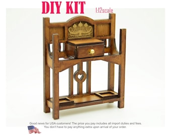 May include: A 1:12 scale wooden DIY kit for a miniature hall stand featuring a dark brown finish, a single central drawer with a small gold-colored knob, a decorative gold-toned metal inlay at the top, and a heart-shaped cutout in the center frame.