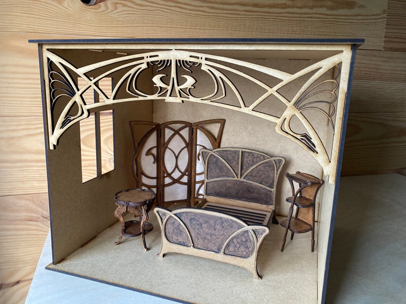 May include: A miniature wooden dollhouse room with a bed, two side tables, and a screen. The room is decorated in an Art Nouveau style with intricate wooden details.