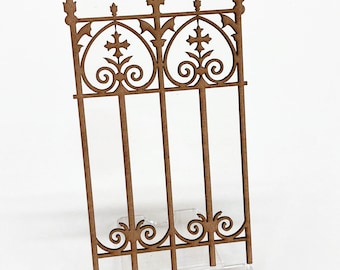 May include: A wooden cutout of a decorative gate with a gothic design. The gate is made of brown wood and has a detailed design with crosses and swirls.