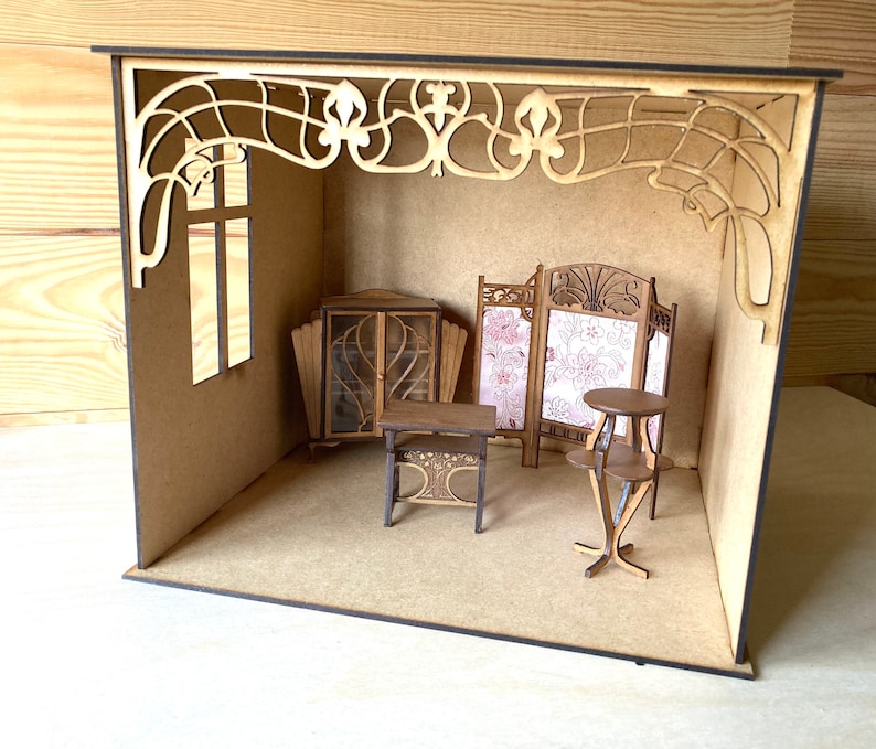 May include: A miniature dollhouse room with wooden furniture, including a bookcase, a table, and a screen. The room has a decorative wooden archway and a window.