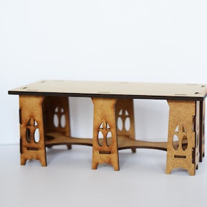May include: A wooden table with a rectangular top and intricate cutouts on the legs. The table is made of light brown wood and has a rustic appearance.