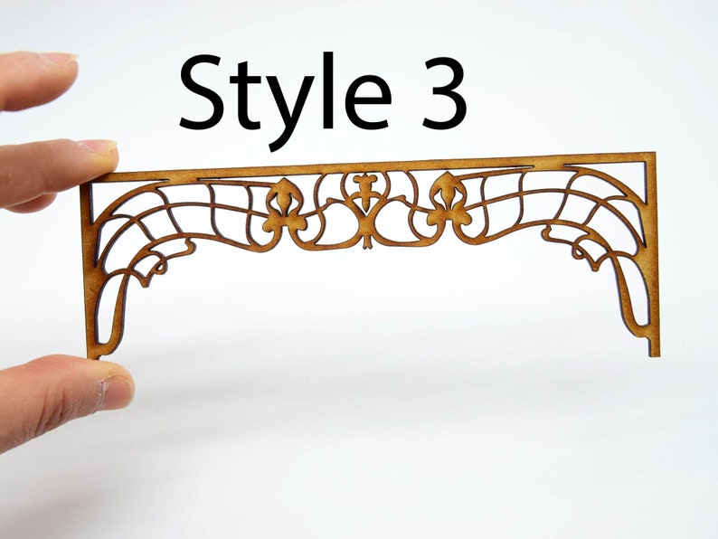 May include: A wooden decorative arch with a delicate, intricate design. The arch is made of thin, laser-cut wood and features a repeating pattern of swirls and curves. The arch is a light brown color and has a slightly distressed finish. Style 3.
