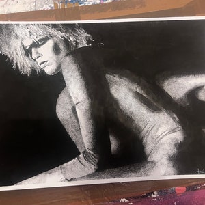 May include: Black and white photograph print of a person with short, spiky hair. The person is lying on their side with their back to the camera. The photo is signed in the bottom right corner.